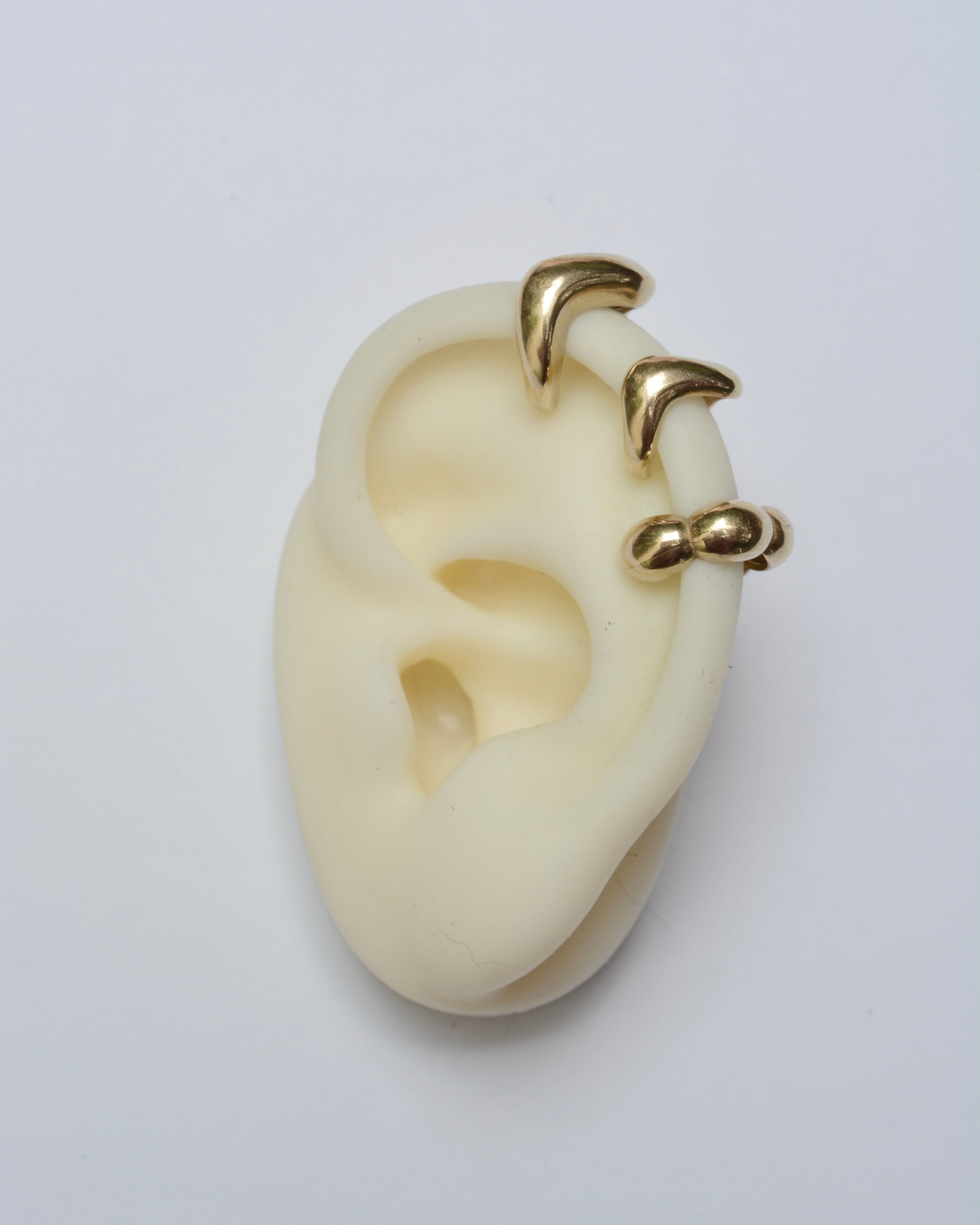 Gold ear cuffs on a white ear model against a light gray background