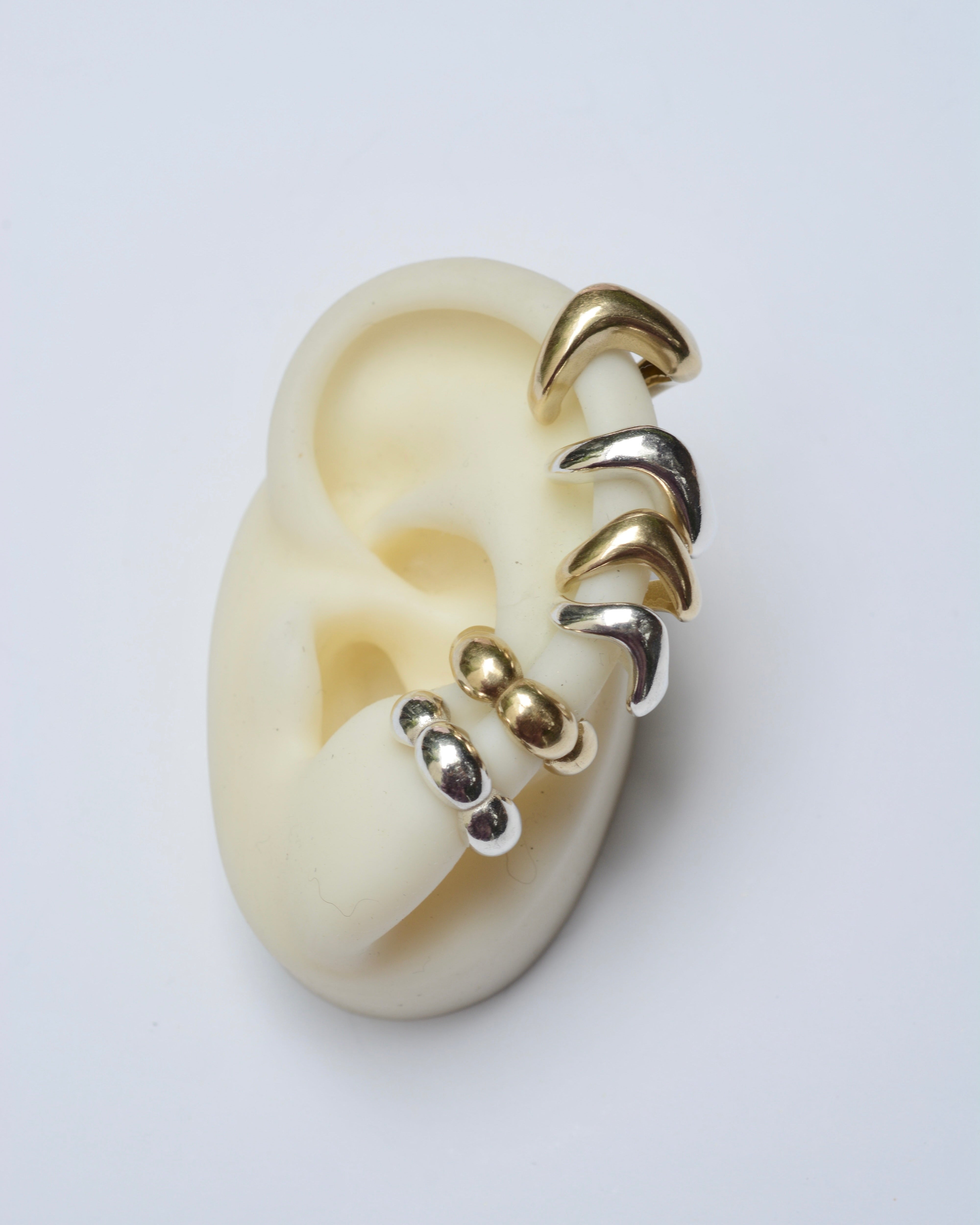 Ear cuffs in silver and bronze on a white ear