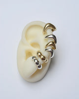 Ear cuffs in silver and bronze on a white ear