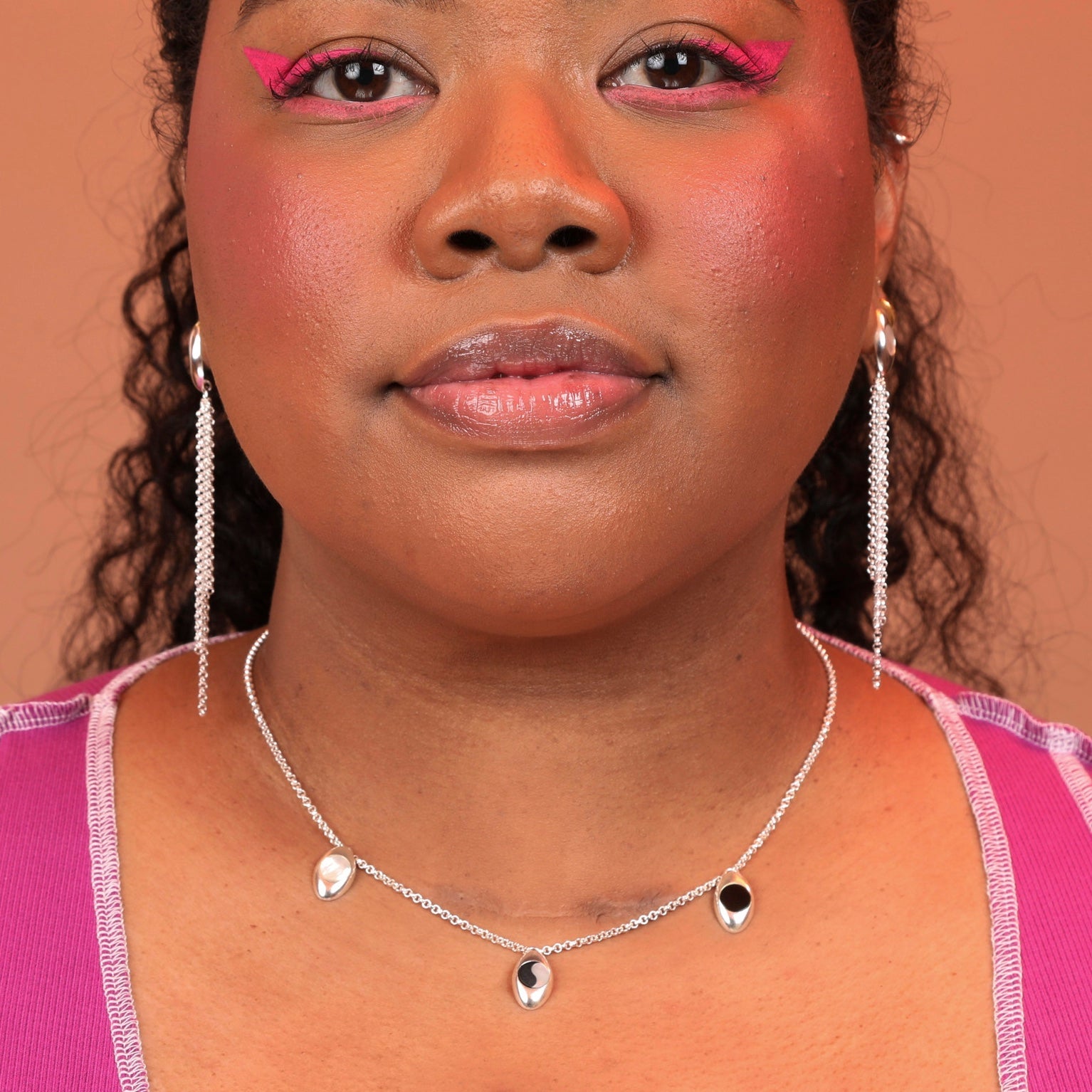 Person wearing a silver necklace with pendant charms in different stones