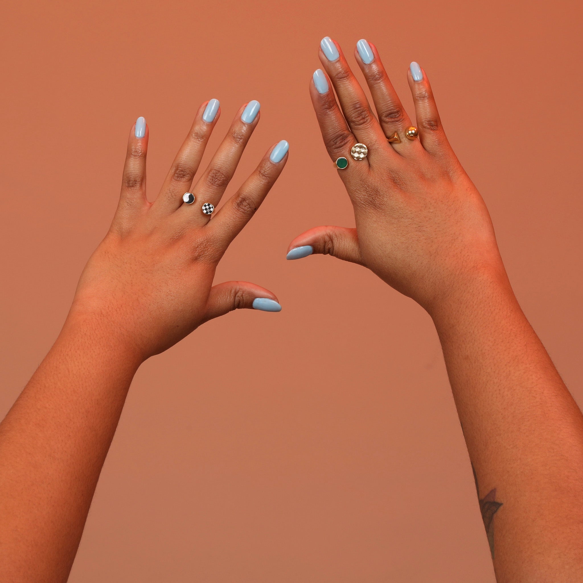 Two hands wearing an assortment of bronze rings with adjustable split shank designs