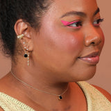 A person wearing a choker necklace with a dainty chain and black onyx pendant