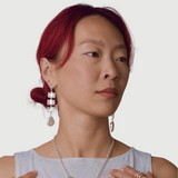 Woman wearing silver coral shaped dangle earrings with pearls at the bottom