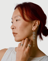 Woman wearing long dangly earrings and rings on a white background