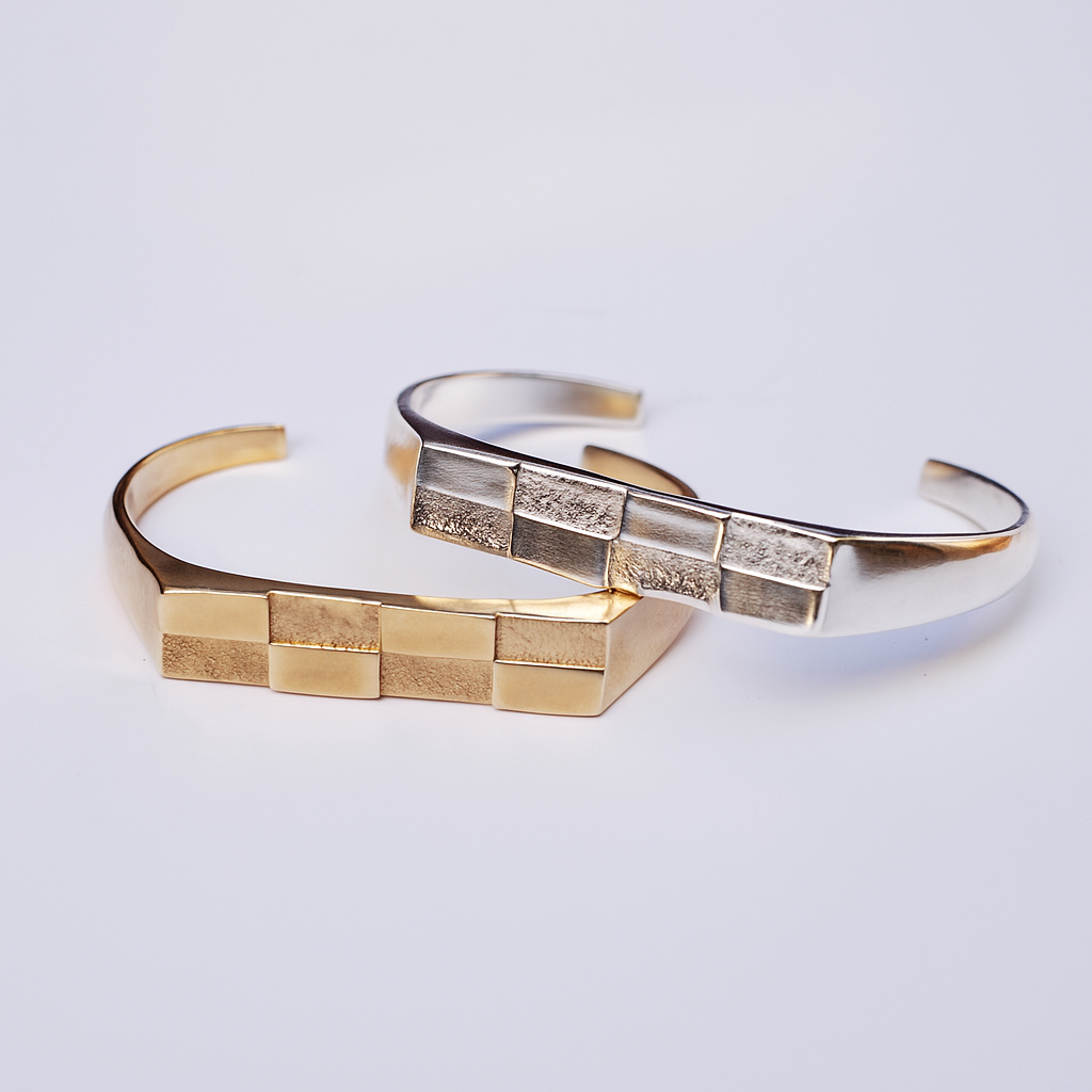 a bronze and silver checkerboard cuff sitting on a grey background