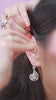 person putting on a silver ear cuff